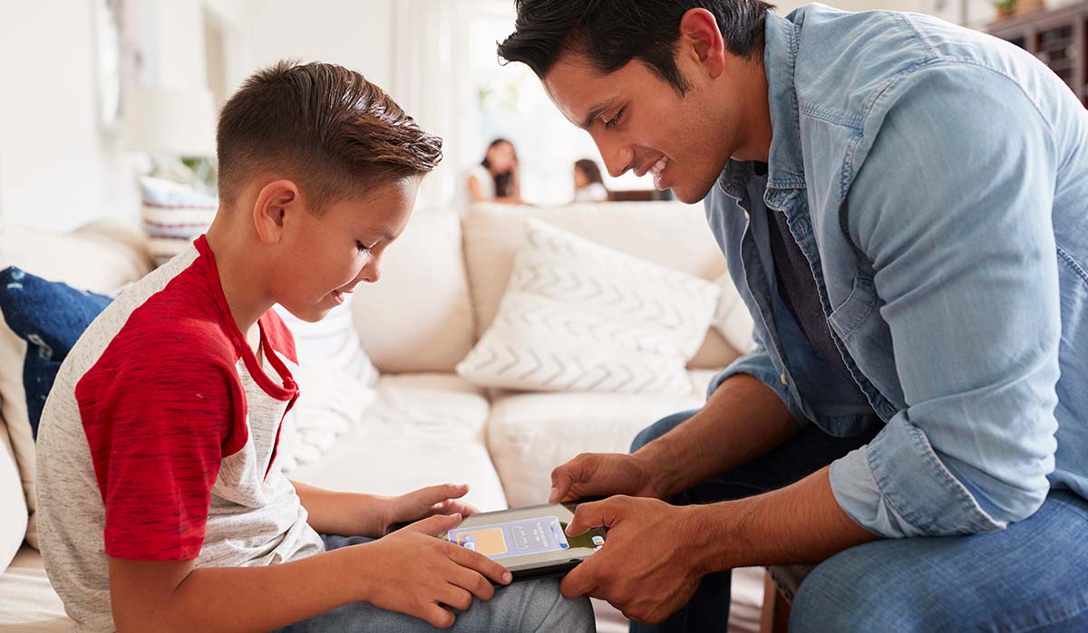 Latino father showing his son how to navigate on his tablet