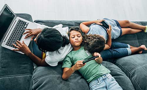 Niños en casa usando diferentes dispositivos conectados al mismo tiempo